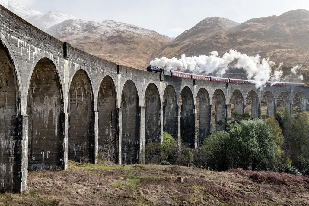 Ein Bild von einer Lokomotive, die über eine Brücke fährt und von einer schönen Landschaft eingerahmt wird